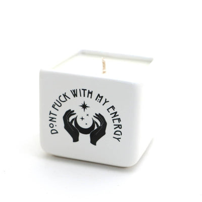 The Lenny Mud Dont F With My Energy 8oz hand-poured soy candle comes in a white ceramic pot with bold black text and art of hands holding a crescent moon and stars—an unscented candle that adds attitude to any space.