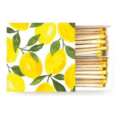 The Lemon Candle Matches in Box by Abigail Jayne Design feature vibrant watercolor lemon and green leaves on the lid. The partially open box reveals rows of matchsticks with striking yellow tips.