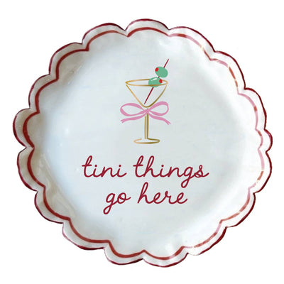 The Tini Things Trinket Dish by soiree-sisters is a scalloped white ceramic tray with a red rim, martini glass design, and "tini things go here" in red cursive—a perfect dresser accessory or charming gift.