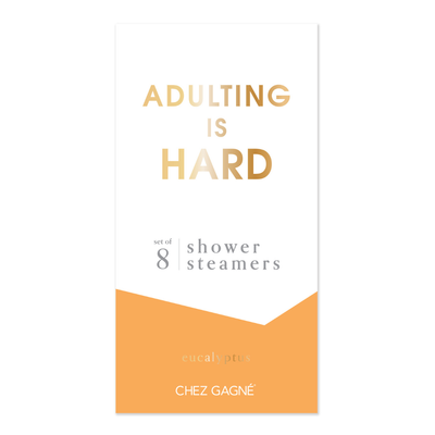 White and orange packaging with gold text reads Adulting is Hard. Below, it says Shower Steamers Set with eucalyptus essential oil. The brand, Chez Gagné, appears at the bottom. Made in USA.