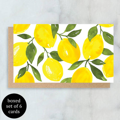 The Abigail Jayne Design Lemon Mini Cards, a boxed set of 6, feature watercolor artwork with vibrant yellow lemons and lush green leaves. They come nestled in a recycled kraft envelope against a marble background, with a black circle announcing the set details.