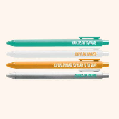 The Showgirl Pen Set by MangoIllustrated includes 4 novelty pens in teal, white, gold, and silver with black gel ink and fun phrases—perfect for adding flair to your writing routine.