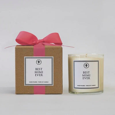 A brown box with a pink ribbon lies beside a glass jar candle labeled Best Mimi Ever by Ella B Candles. This white, hand-poured pure soy candle emits a Sea Mist & Jasmine scent and offers over 60 hours of burn time.