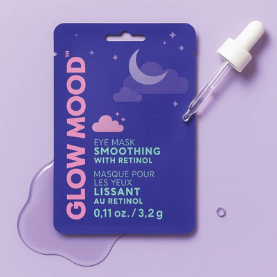 A purple sachet of Glow Mood Smoothing Eye Mask with Retinol lies on a lavender surface with a dropper and serum, featuring dreamy clouds, stars, and a crescent moon on the packaging. The mask helps reduce puffiness and dark circles.