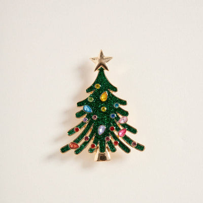 The Glitter Christmas Tree Brooch Pin by Designature New York features colorful rhinestones on green branches with a gold star topper, displayed against a plain white background.