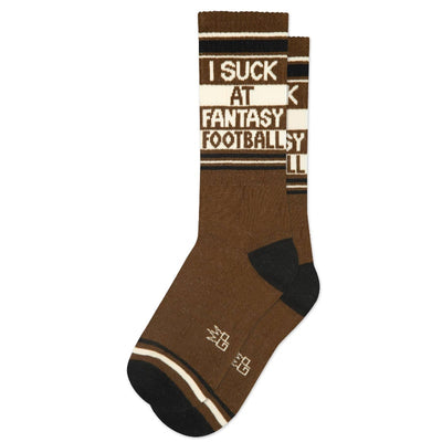 Gumball Poodle’s “I Suck At Fantasy Football Gym Crew Socks” are brown unisex socks with black heels and toes, featuring white stripes and bold text—perfect for playful sports fans.