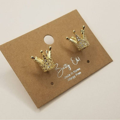 A pair of gold Crown Post Earrings with sparkling cubic zirconia on a brown card labeled BETTYOH INC. Made in Korea, Allergy Free.