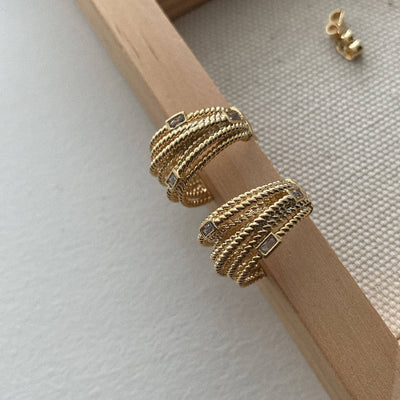 The musthavemustget Multi Wrap Hoop Earrings feature a gold twisted rope design with small baguette-cut CZ stones and stud backings, displayed on the corner of a wooden frame.