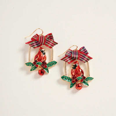 The Golden Stella Christmas Cardinal on Perch Earrings feature 1.75" red cardinals perched among green holly leaves with berries, gold oval frames, striped bows, and a red jingle bell. Made in China from zinc.