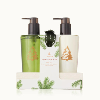 Two bottles of Thymes Frasier Fir hand care products in a ceramic caddy on a white background