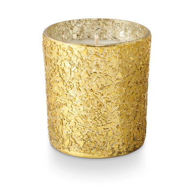 The Illume Candles Glittering Garland Glitter Glass Candle is a gold vegan candle in a textured, crackled glass holder, displayed against a white background.