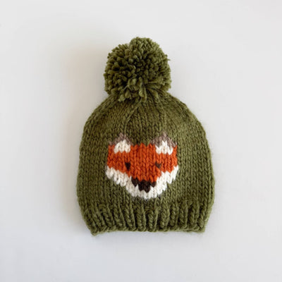 Knitted green baby hat with fox face design on a white background