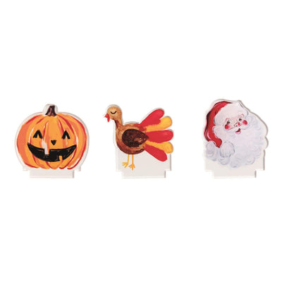 Mud Pie’s Light-Up Holiday Countdown Set features three illustrated cutouts—a jack-o’-lantern, a turkey, and Santa Claus—displayed on a white background with a charming wooden countdown block.