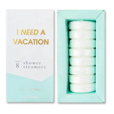 The I Need a Vacation shower steamers by Chez Gagne are revealed in light turquoise and white packaging with gold and gray text. Inside are eight coconut lime-scented steamers, offering an escape enhanced by essential oils.