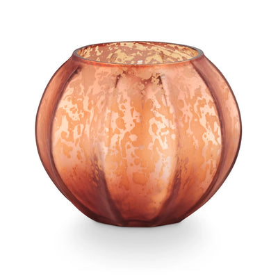 The Midnight Pumpkin Mercury Pumpkin Candle by Illume Candles features a round, pumpkin-shaped glass vessel with a mottled orange and gold finish—ideal for autumn decor or pairing with a birch wood candle.