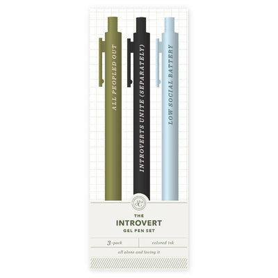 The Introvert Pen Set by Studio Calico includes three gel pens—olive green, black, and light blue—labeled ALL PEEPED OUT, INTROVERTS UNITE (SEPARATELY), and LOW SOCIAL BATTERY. A must-have stationery 3-pack with colored ink.
