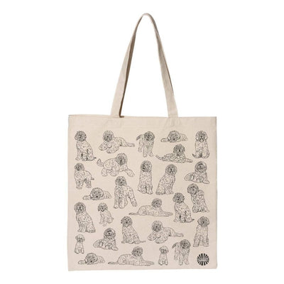 The Sween Shop Labradoodle Canvas Tote Bag is a beige cotton tote with playful doodle-style dog drawings, two handles, and a small circular logo at the bottom right corner. Perfect for reusable shopping.