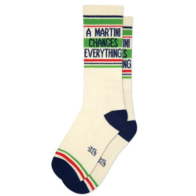 Gumball Poodle's "A Martini Changes Everything" Unisex Gym Crew Socks feature a cream base, navy toes and heels, green and red stripes, and “A MARTINI CHANGES EVERYTHING” knit in block letters around the cuffs.