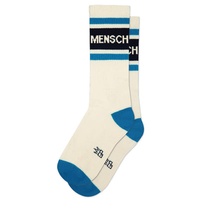 Gumball Poodles Mensch Gym Crew Socks are white crew socks with blue toes, heels, and top stripes. MENSCH is boldly printed on the black band. These unisex socks are ideal for everyday wear.