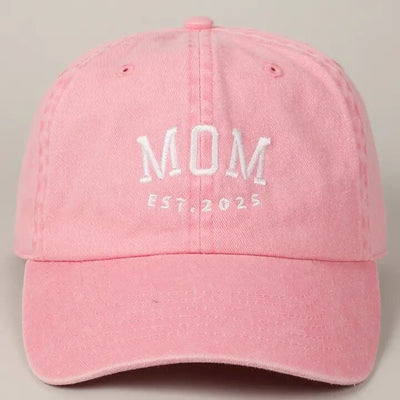 The Fashion City Mom Est. 2025 embroidered pink cotton baseball cap features white text on the front and an adjustable strap for a perfect fit, set against a plain background.