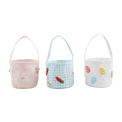 Mud Pies Beaded Easter Baskets offer three charming choices: a pink gingham cotton basket with embroidered bunnies and eggs, a blue gingham basket featuring bunnies and carrots, and a white basket decorated with colorful eggs. All have handles for easy carrying.