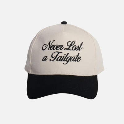 The "Never Lost A Tailgate" Embroidered Two Tone Baseball Cap by Judson & Company features a white crown, black brim, black cursive embroidery on the front, and a snap back closure. Made from 100% cotton; one size fits most.