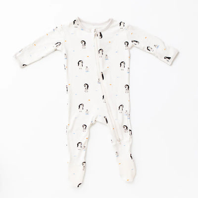 The Bamboo Little Penguin Zippered Footie is a white long-sleeve bamboo baby sleeper with feet, decorated with penguin and snowman prints. It features a soft viscose material and a diagonal neck-to-leg zipper.