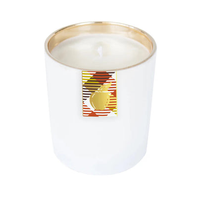 The Orchard Boxed Candle by Annapolis Candle is a white scented candle in a glossy glass jar with a gold interior. Its front label displays red, gold, black, and white stripes plus a central gold apple for festive appeal.