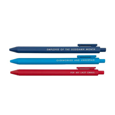 The Pens for the Overworked set by Tiny Hooray features three pens: a blue one with Employee of the Goddamn Month, a dark blue pen with bold black gel ink saying Overworked and Underpaid, and a red pen stating Per My Last Email.