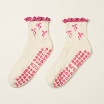 Pair of socks with pink bows and hearts on a beige background