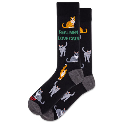 HOTSOX Mens Real Men Love Cats Crew Socks feature black cotton with gray toes/heels, playful gray and orange cat designs, and REAL MEN LOVE CATS in green/white. Fits men’s shoe size 6–12.5.