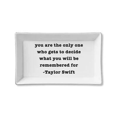 The Remembered for Taylor Swift Quote Ceramic Tray by Toss Designs is a stylish, rectangular ceramic trinket tray that makes a perfect gift. It features a black text quote: you are the only one who gets to decide what you will be remembered for - Taylor Swift, ideal for organizing your space.