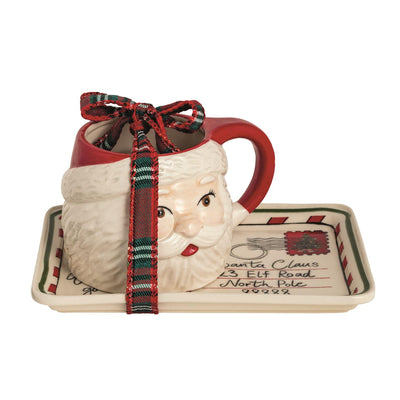 The Mud Pie Santa Postcard Tray & Mug Set includes a ceramic Santa mug with a red handle and a stoneware tray styled as a North Pole letter, both tied with a plaid ribbon for a festive holiday serving set.