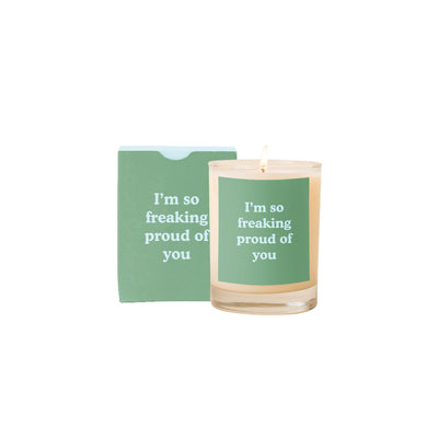 The So Freaking Proud Of You Candle by Talking Out of Turn comes in a glass holder with a green label featuring an uplifting quote. Made with soy-based wax and paraben-free fragrances, it is packaged in a matching green box displaying the same inspiring message against a white background.