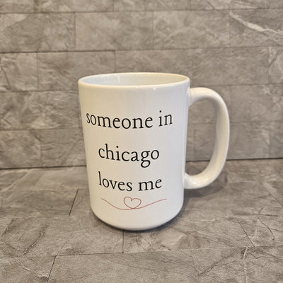 The Someone in Chicago Loves Me mug by Boho Sips is a white ceramic microwave-safe mug with someone in chicago loves me in black lowercase letters above a small heart design, all sublimated for durability, set against a textured grey tiled background.