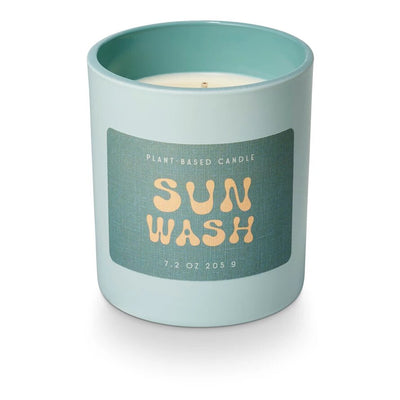 A light blue Sun Wash Sun Glass Candle by Illume Candles in a matching holder includes an embossed label, Plant-Based Candle, Sun Wash, with bergamot and driftwood notes, 7.2 oz 205 g.