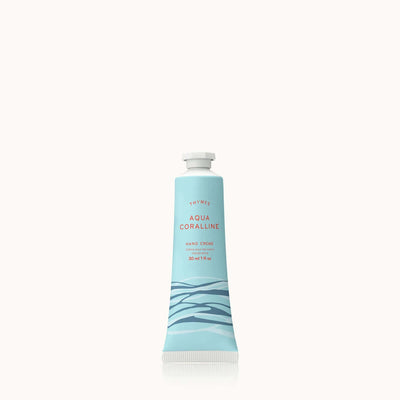 A light blue tube of Aqua Coralline Petite Hand Creme by Thymes features an ocean wave design, is infused with Shea Butter, and includes brand and product details in red. The 30 ml (1 fl oz) tube is set against a plain, light background.