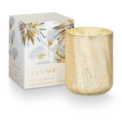 A gold-textured candle holder sits beside Illume Candles' Winter White Small Boxed Crackle Glass Candle, decorated with gray and gold floral accents—a perfect gift candle with a luxurious sandblasted finish.