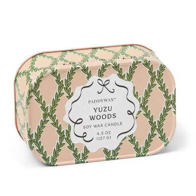The Paddywax Yuzu Woods Cherie Printed Tin Candle is a 4.5 oz rectangular soy wax candle with two wicks, a white front label, and a pink tin decorated with green leafy patterns.