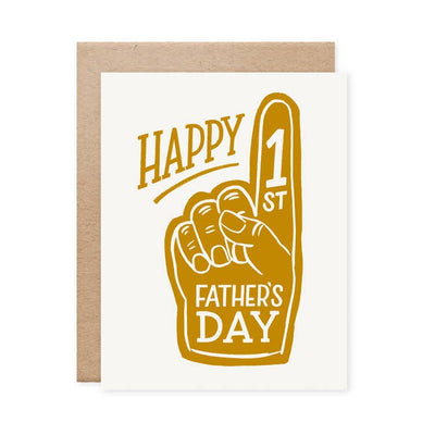 The Naomi Paper Co.s Happy 1st Fathers Day card showcases a brown foam finger graphic with a raised index finger. Ideal for new dads, it includes a plain brown envelope.