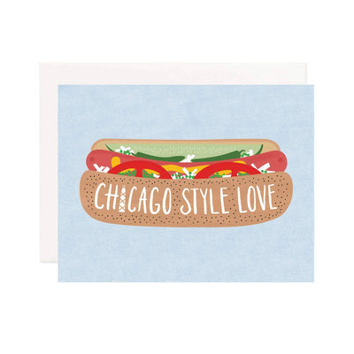 The Chicago Style Love Greeting Card by Pineapple Sundays Design Studio is printed on recycled paper and features a Chicago-style hot dog topped with mustard, relish, onions, tomato slices, and sport peppers. The bun showcases Chicago Style Love against a light blue background.