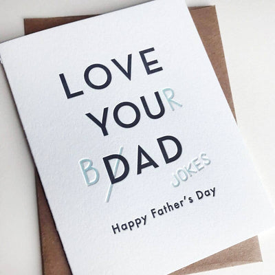The Steel Petal Press Dad Jokes Fathers Day Card is a white letterpress card made in Chicago from recycled cotton rag, featuring LOVE YOUR DAD humorously changed to BAD JOKES and Happy Fathers Day below, paired with a brown envelope.