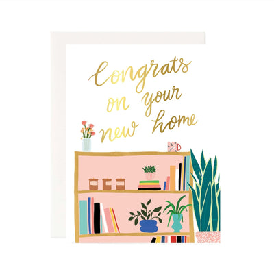 The Pineapple Sundays Design Studios Congrats on the New Home Gold Foil Card features elegant gold foil text and a charming bookshelf against a white background. Ideal for new homeowners, it offers space inside for your personal message.